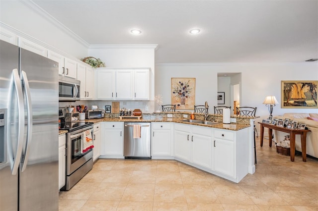 kitchen with a peninsula, stone countertops, a sink, decorative backsplash, and stainless steel appliances