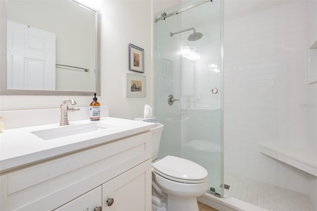 bathroom with toilet, a stall shower, and vanity