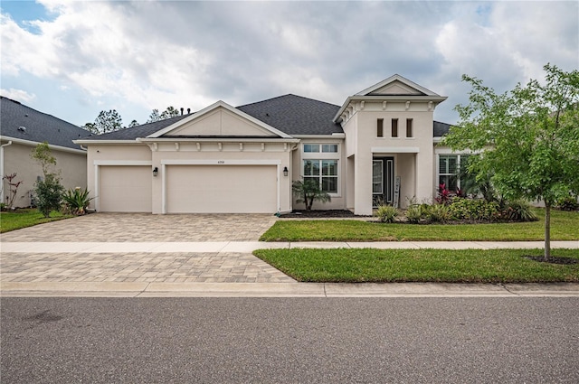 view of front of home with stucco siding, decorative driveway, a front lawn, and an attached garage