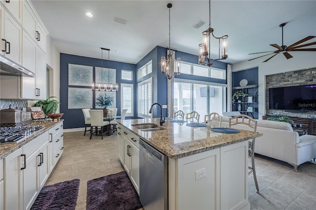 kitchen featuring stainless steel appliances, ceiling fan with notable chandelier, a sink, open floor plan, and a center island with sink