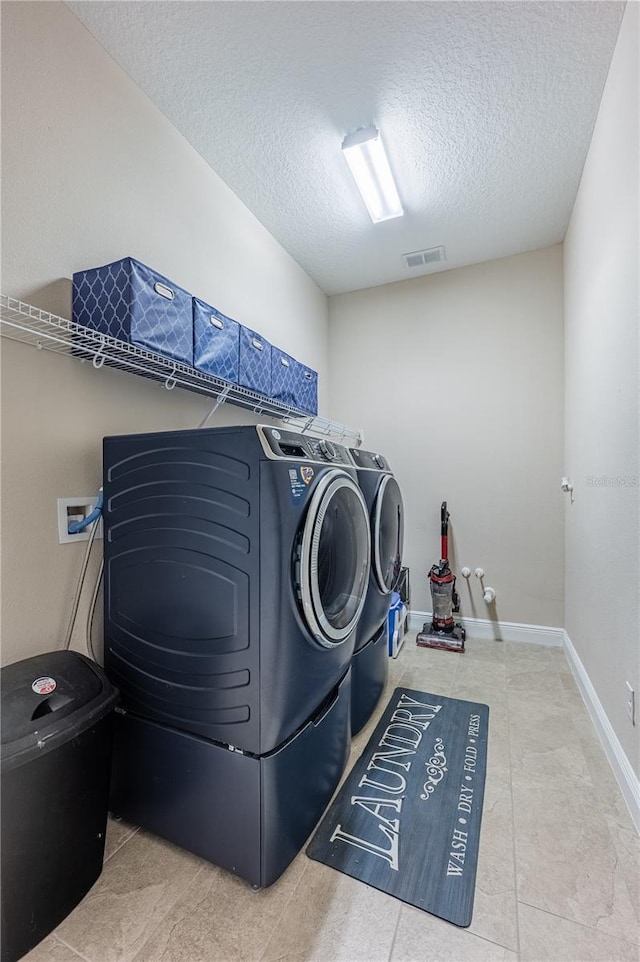 laundry area with separate washer and dryer, laundry area, baseboards, visible vents, and a textured ceiling