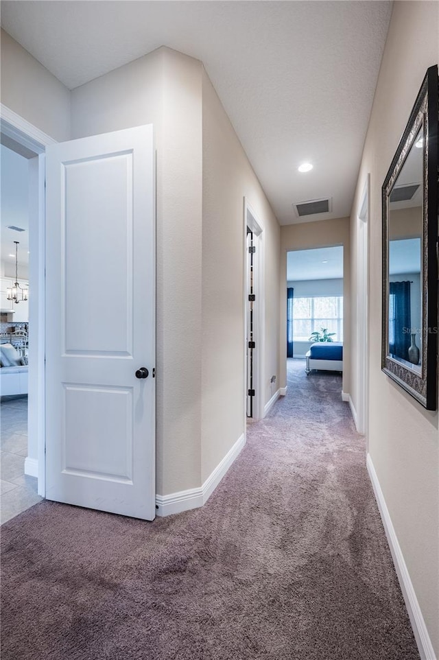 hallway with carpet flooring, baseboards, and visible vents