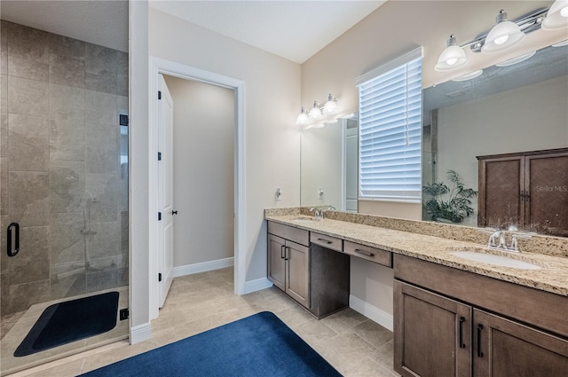 full bathroom with double vanity, a sink, a shower stall, and baseboards