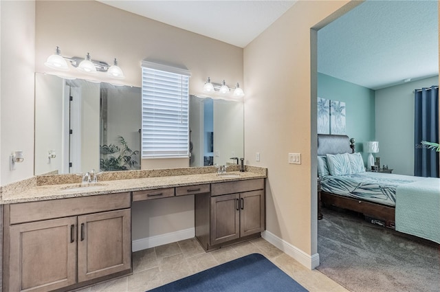 full bathroom featuring double vanity, a sink, baseboards, and ensuite bathroom