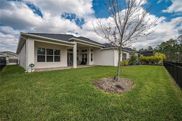 rear view of property with a fenced backyard, stucco siding, and a lawn
