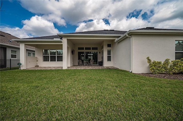 rear view of property featuring a lawn, fence, stucco siding, and a patio area