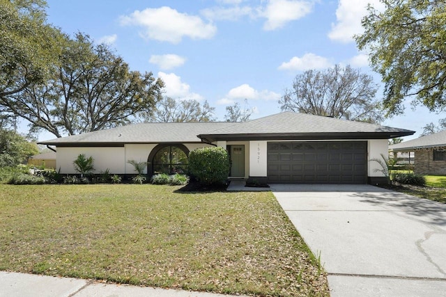 single story home featuring a front yard, driveway, an attached garage, and stucco siding