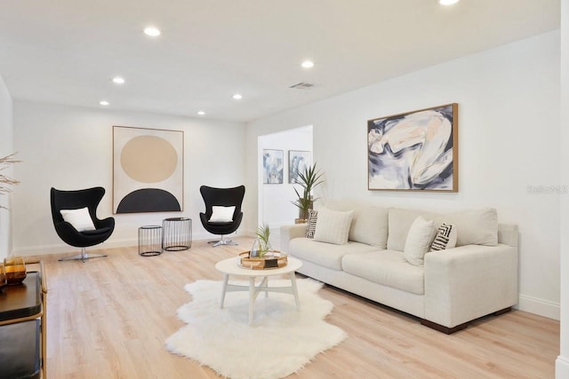 living room featuring light wood-style floors, baseboards, visible vents, and recessed lighting