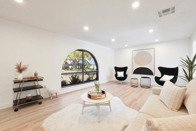 living room with recessed lighting, visible vents, and wood finished floors