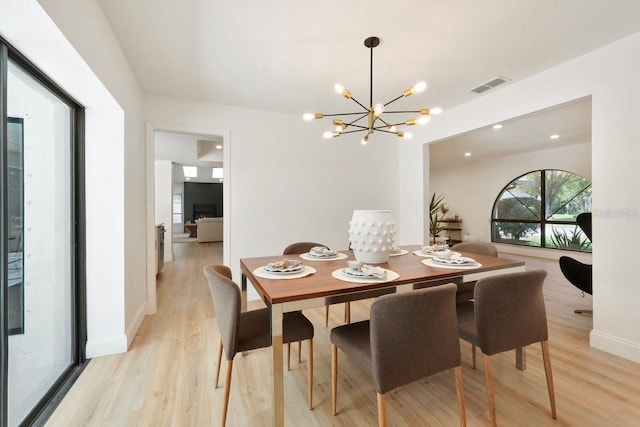 dining space with light wood finished floors, baseboards, a fireplace, and visible vents