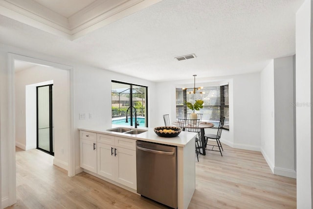 kitchen featuring visible vents, stainless steel dishwasher, white cabinets, a sink, and light wood-type flooring