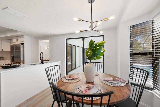 dining area featuring a textured ceiling, light wood finished floors, and an inviting chandelier