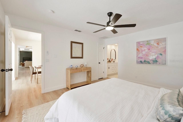 bedroom with visible vents, baseboards, a ceiling fan, light wood-style flooring, and ensuite bathroom