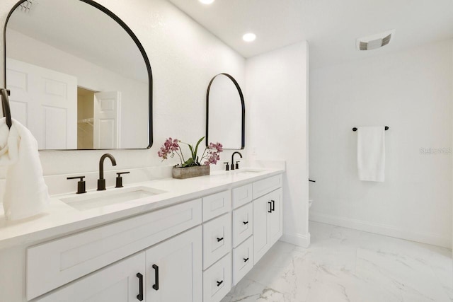 full bathroom featuring double vanity, marble finish floor, baseboards, and a sink