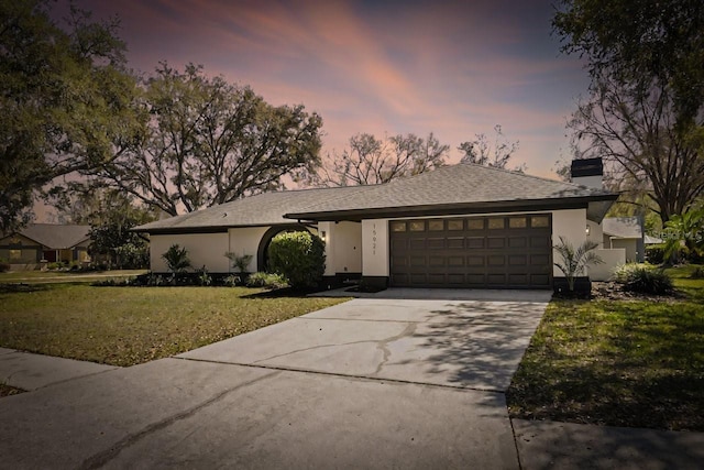 view of front of home with a garage, concrete driveway, a yard, and a chimney