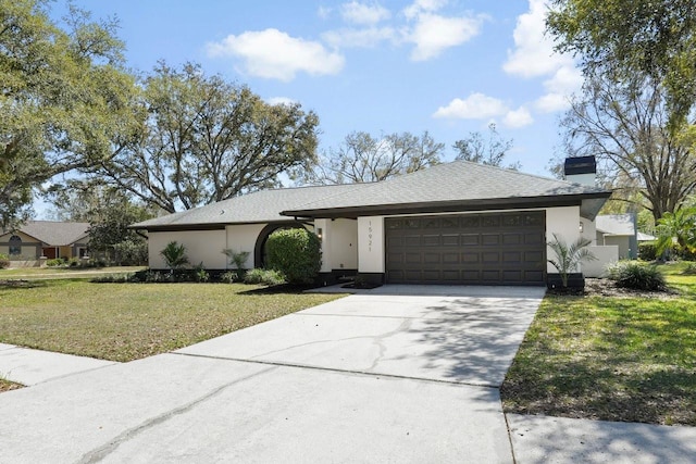 view of front facade with a chimney, stucco siding, concrete driveway, an attached garage, and a front lawn