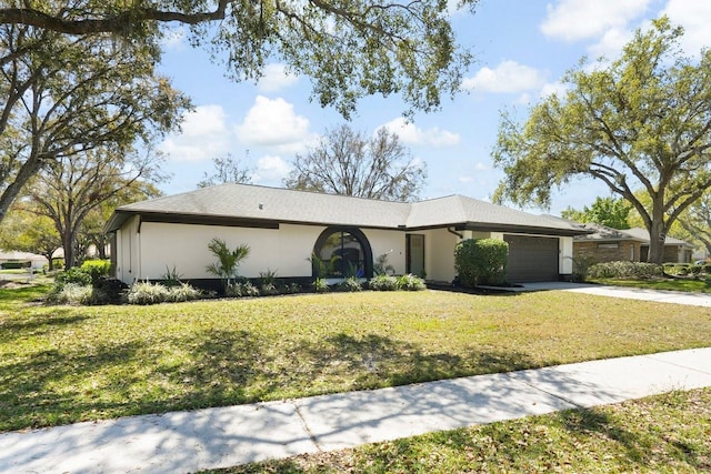 view of front of property featuring driveway, stucco siding, a garage, and a front yard