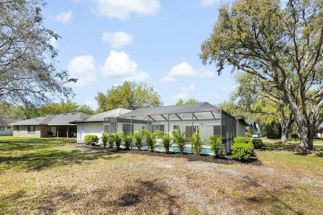 rear view of property with glass enclosure and a yard