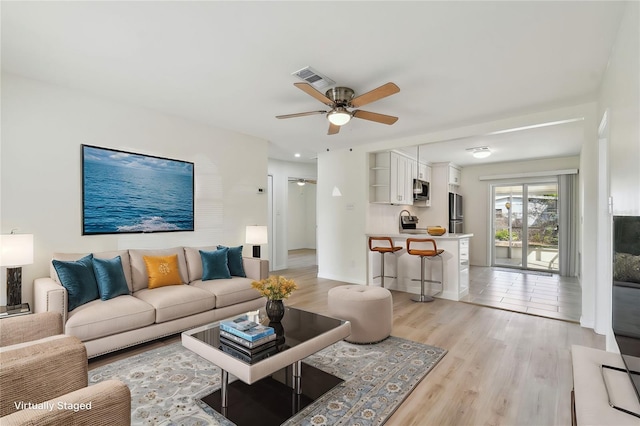 living area with visible vents, ceiling fan, and light wood-style floors