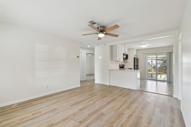 unfurnished living room featuring visible vents, baseboards, light wood-style flooring, and a ceiling fan