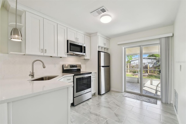 kitchen featuring visible vents, a sink, stainless steel appliances, white cabinets, and light countertops