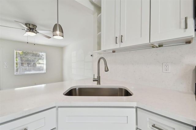 kitchen with a sink, open shelves, light stone counters, white cabinets, and ceiling fan