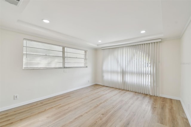 spare room featuring a raised ceiling, wood finished floors, a healthy amount of sunlight, and recessed lighting