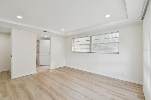 spare room featuring recessed lighting, light wood-style flooring, and a raised ceiling