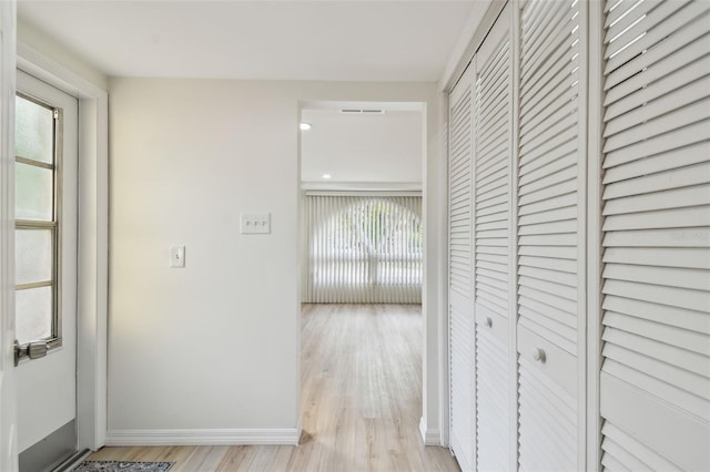 corridor featuring visible vents, light wood-style floors, and baseboards