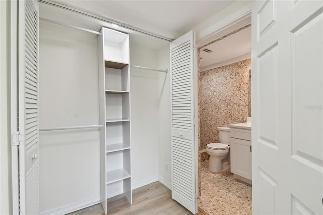 bathroom with a closet, toilet, vanity, and wood finished floors