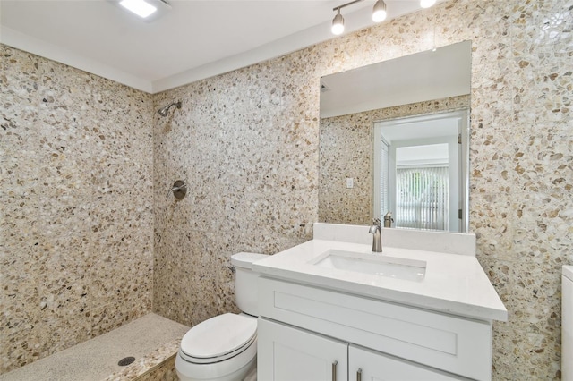 full bath featuring tiled shower, toilet, and vanity