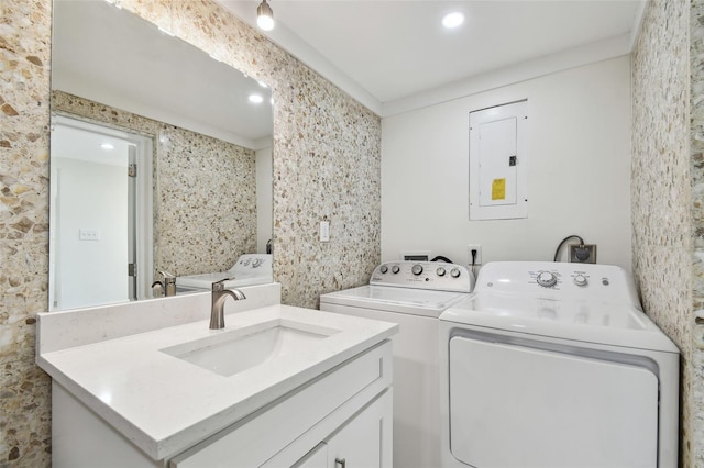 washroom featuring laundry area, electric panel, washing machine and dryer, and a sink