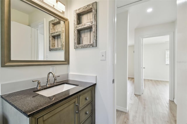 bathroom with vanity, recessed lighting, wood finished floors, and baseboards