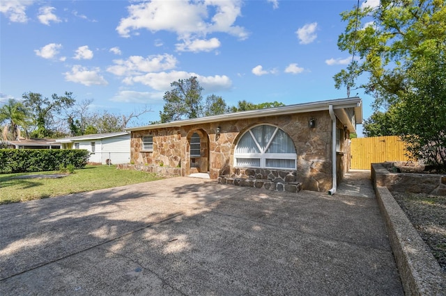 view of front of house featuring a gate, stone siding, a front lawn, and fence