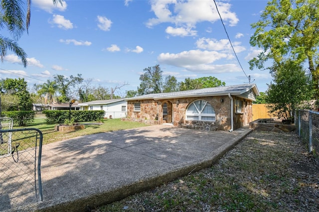 view of front of home featuring stone siding, a fenced backyard, and a front yard