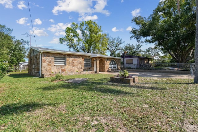 view of front of property featuring stone siding, a front lawn, and fence