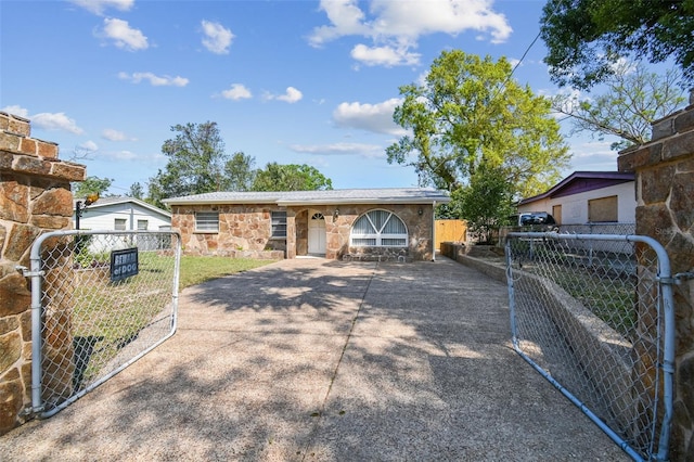 view of front facade featuring a gate, stone siding, and fence