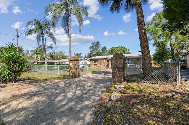 view of front of home with a fenced front yard, stone siding, and a gate