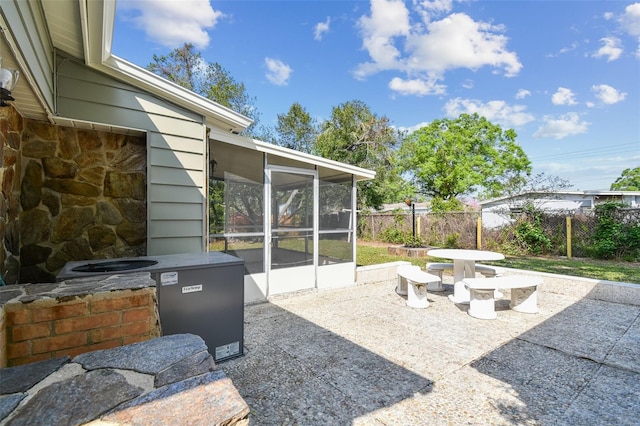 view of patio / terrace featuring fence, outdoor dining space, and a sunroom