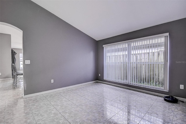 spare room with arched walkways, plenty of natural light, tile patterned flooring, and lofted ceiling