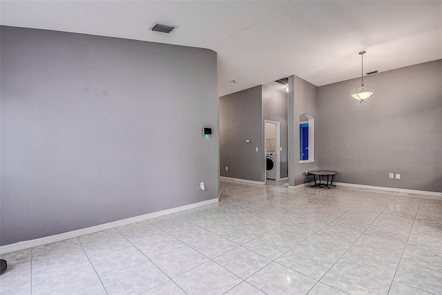 spare room featuring arched walkways, lofted ceiling, visible vents, baseboards, and washer / dryer