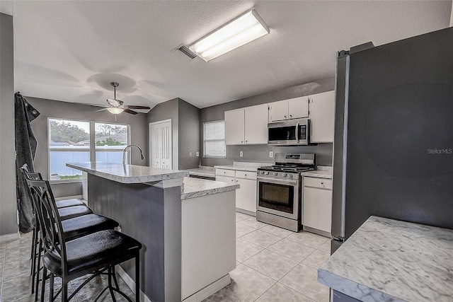 kitchen with light tile patterned floors, light countertops, visible vents, appliances with stainless steel finishes, and white cabinets