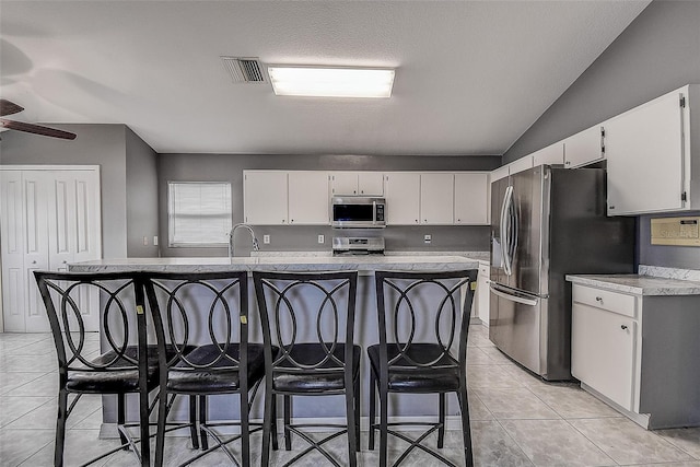 kitchen with appliances with stainless steel finishes, a sink, visible vents, and white cabinetry