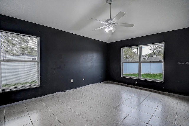 empty room with lofted ceiling, tile patterned flooring, and a ceiling fan