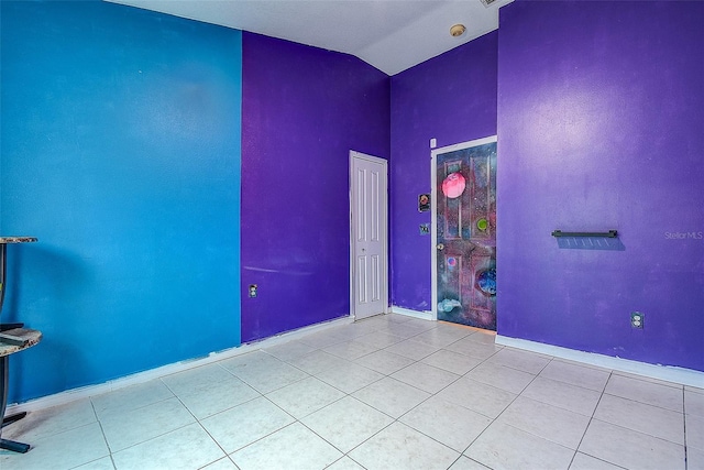 unfurnished room with light tile patterned floors, baseboards, and vaulted ceiling