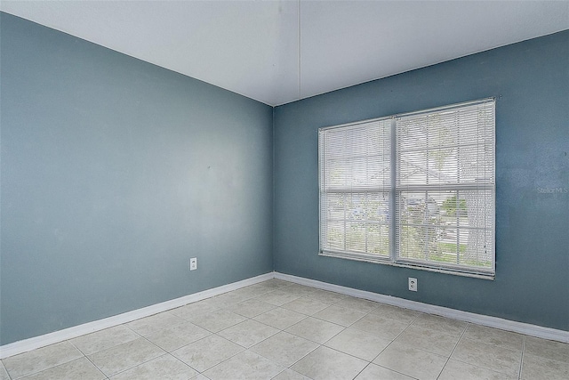 empty room featuring baseboards and light tile patterned flooring