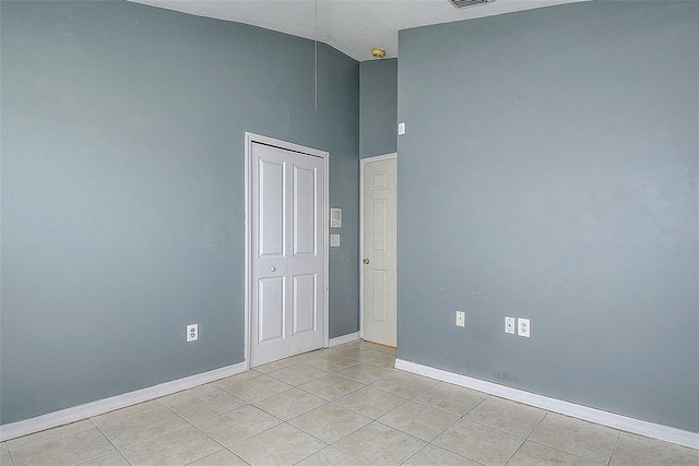 spare room featuring high vaulted ceiling, visible vents, baseboards, and light tile patterned flooring