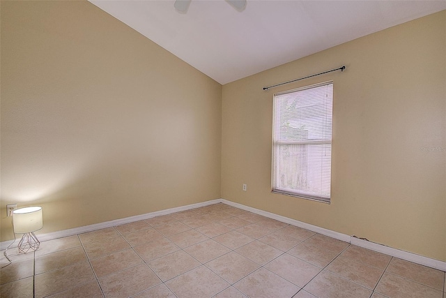 empty room featuring lofted ceiling, baseboards, and light tile patterned flooring