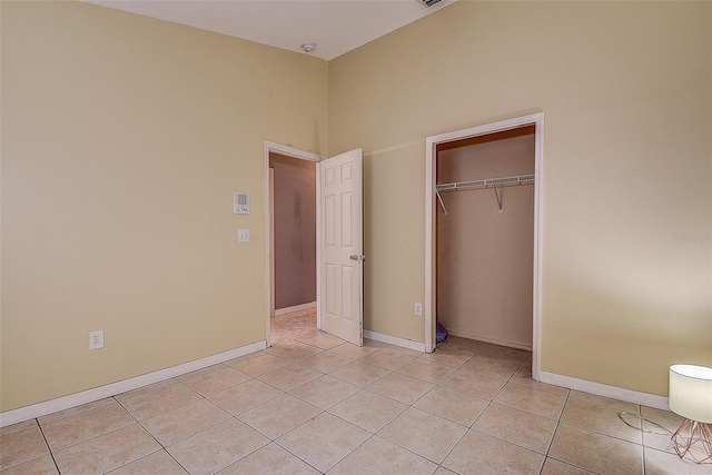 unfurnished bedroom featuring light tile patterned floors, a closet, and baseboards