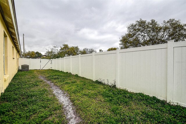 view of yard with a fenced backyard and central AC unit